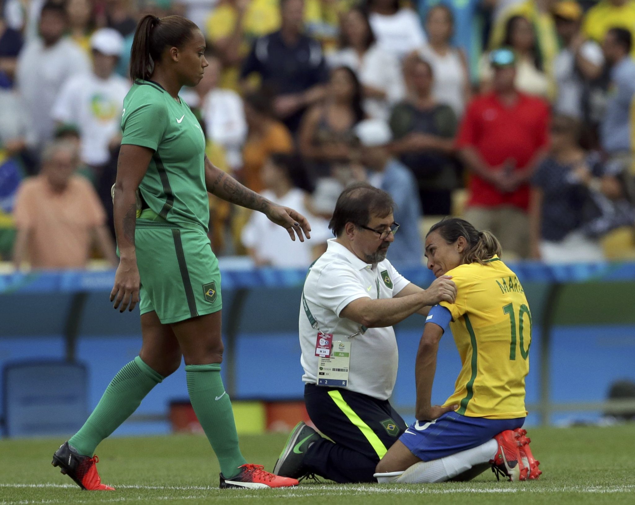 2016 Rio Olympics - Soccer - Semifinal - Women's Football Tournament Semifinal Brazil v Sweden - Maracana - Rio de Janeiro, Brazil - 16/08/2016. Marta (BRA) of Brazil is consoled by a team official as goalkeeper Barbara (BRA) of Brazil approaches after the game. REUTERS/Bruno Kelly FOR EDITORIAL USE ONLY. NOT FOR SALE FOR MARKETING OR ADVERTISING CAMPAIGNS.